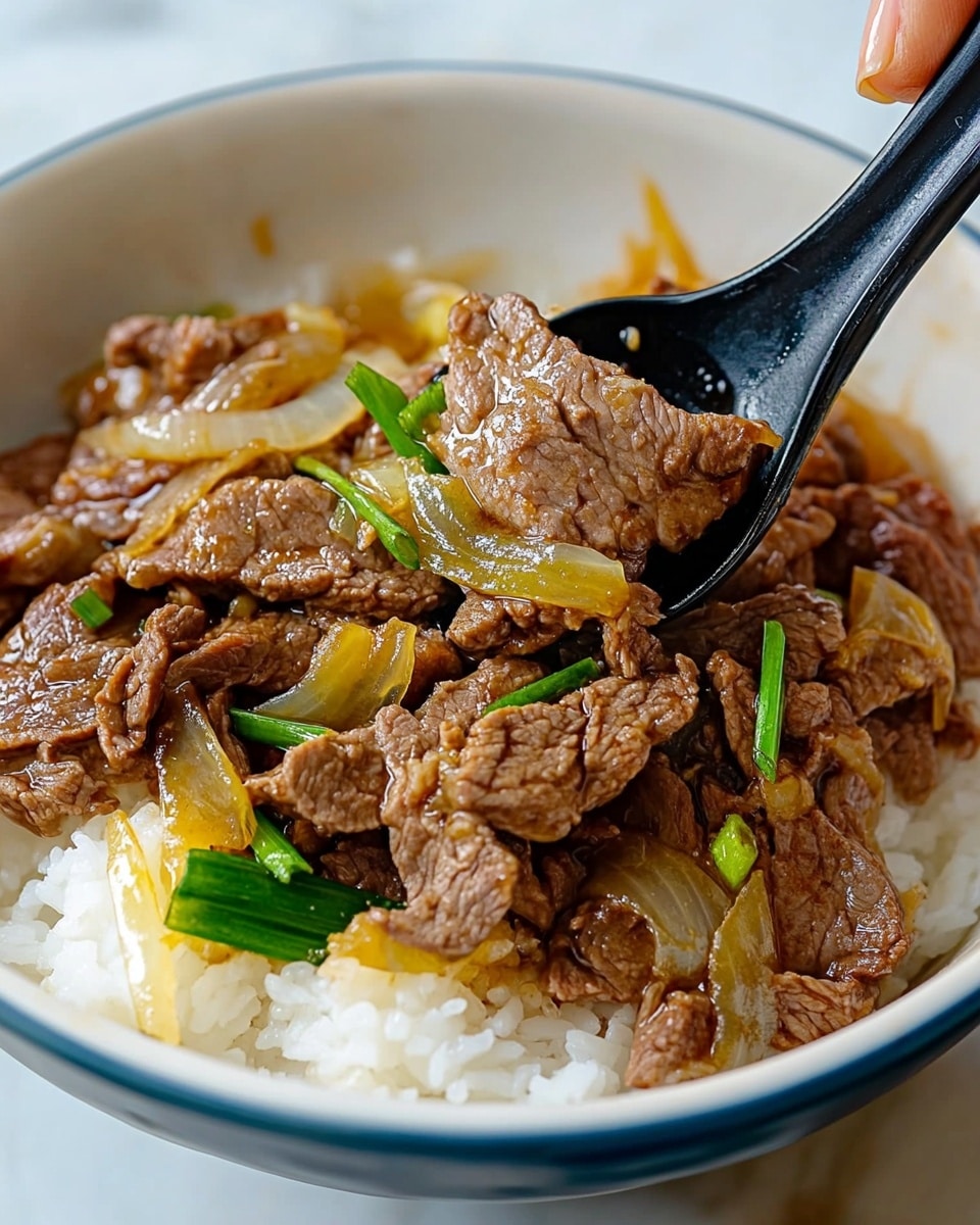 Gyudon Japanese Beef Rice Bowl, Japanese beef bowl recipe, quick Gyudon recipe, savory beef donburi, easy Japanese dinner ideas The image shows a close-up of a white bowl with a blue rim filled with three layers. The bottom layer is white cooked rice with a soft texture. On top of the rice, there is a layer of brown cooked beef pieces mixed with translucent cooked yellow onions and bright green sliced scallions. A black spoon is scooping some beef and onions from the bowl, held by a woman's hand visible on the right side. The bowl sits on a white marbled surface.