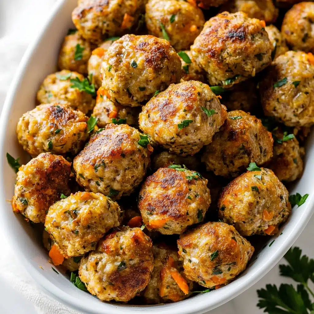 Turkey Stuffing Balls, leftover turkey appetizer, holiday stuffing bites, easy snack recipes, finger food for gatherings A white bowl filled with about 20 round, golden-brown meatballs that have a slightly crispy surface with small bits of herbs and vegetables visible. The meatballs are stacked closely together, with some fresh green parsley leaves scattered on top and around the edges for garnish. The bowl is placed on a white marbled surface with a soft gray cloth partially visible under the bowl. The meatballs have a textured, slightly shiny look showing they are cooked well and seasoned.