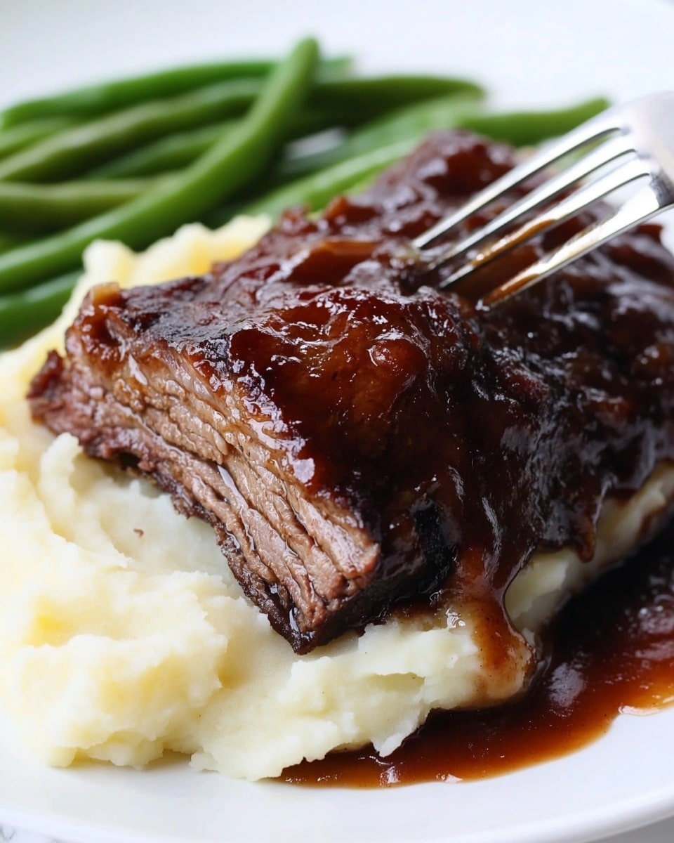 This image shows a white plate with three layers of food. The bottom layer is creamy mashed potatoes with a soft and smooth texture, spread in a thick, rounded shape. On top of the mashed potatoes, there is a large, dark brown grilled pork rib, with a shiny, slightly sticky glaze and visible char marks. To the right of the rib, on the same plate, is a small serving of cooked green beans that are bright green and appear tender but firm. The plate is placed on a white marbled surface and a fork is laying near the bottom edge of the plate. In the background, a woman's hand is holding the plate carefully. Photo taken with an iphone --ar 4:5 --v 6.1