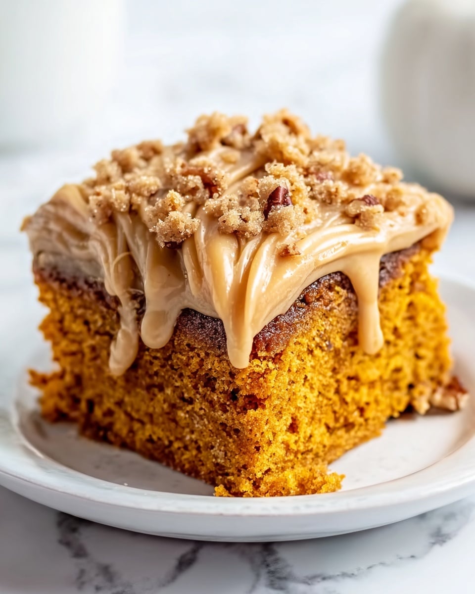 The image shows a single square piece of pumpkin cake placed on a white plate. The cake has two visible layers: a moist orange-brown pumpkin layer at the bottom and a thick, light brown frosting layer on top. The frosting is creamy and smooth, with a darker brown drizzle of caramel sauce poured over, running down the sides in thick streams. The top is sprinkled with small brown crunchy bits for texture. The plate is set on a white marbled surface, and the warm colors of the cake contrast nicely with the background. photo taken with an iphone --ar 4:5 --v 7