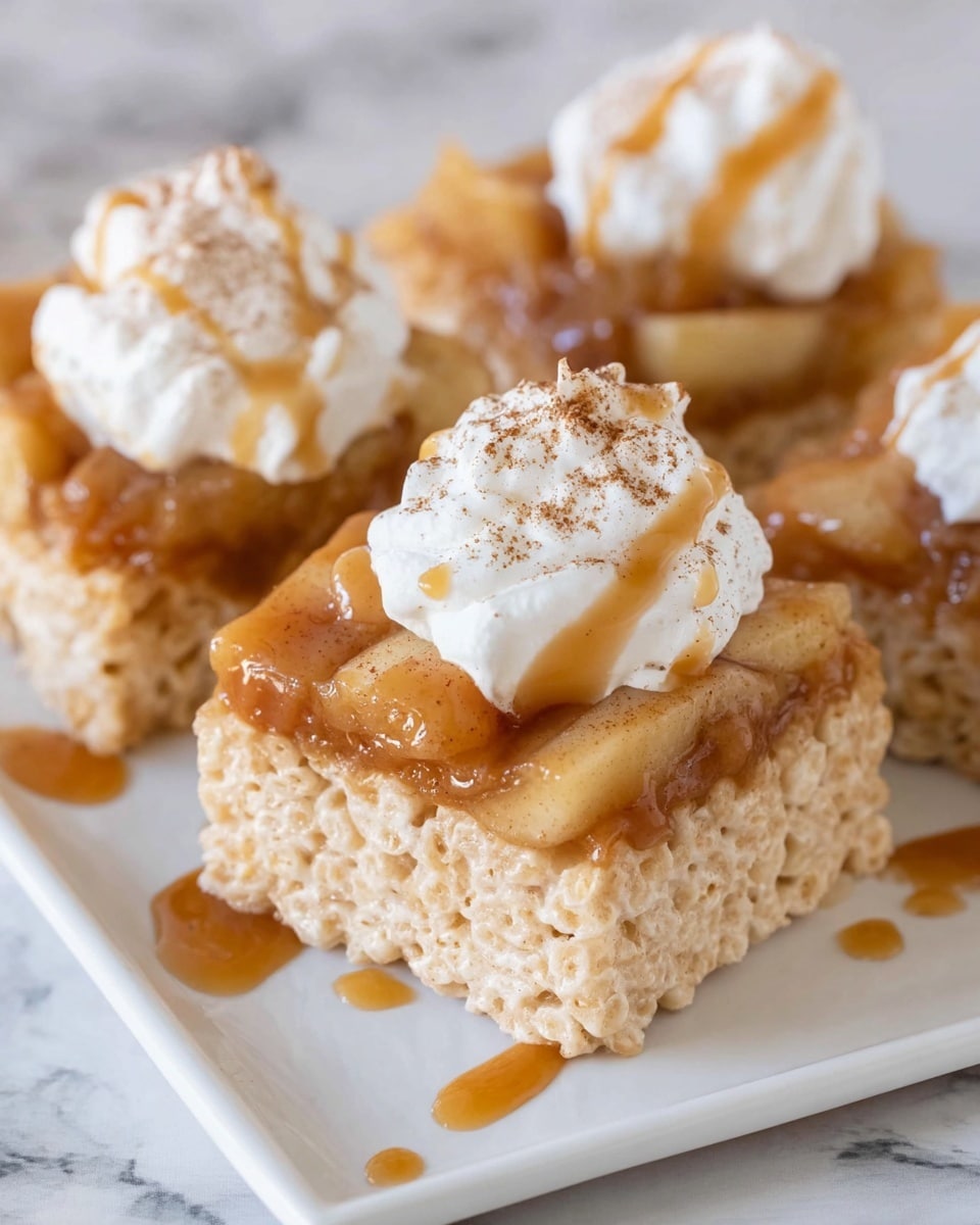 The image shows small square rice crispy treats as the base layer, light beige in color with a soft, airy texture. On top of each treat is a thick layer of caramelized apple pieces, glossy and warm brown in color, with some syrup drizzling slightly down the sides. The top layer is a dollop of white whipped cream, sprinkled lightly with cinnamon powder giving a touch of reddish-brown color. These squares are neatly arranged on a white plate set on a white marbled surface. Photo taken with an iphone --ar 4:5 --v 7
