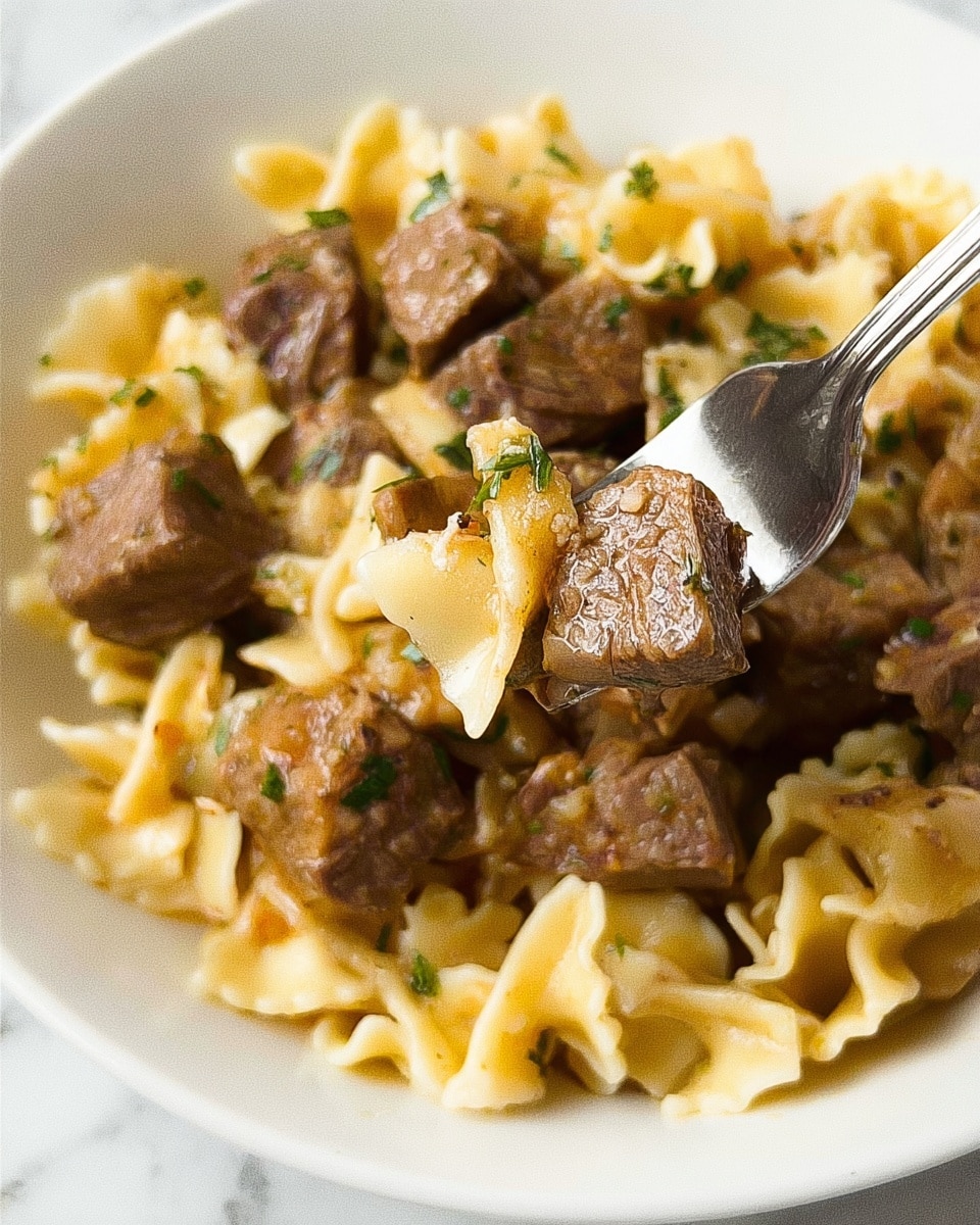 This image shows a close-up of a white bowl filled with layered food. The bottom layer is light yellow pasta with short, twisted shapes and soft texture. On top of the pasta, there are chunky pieces of brown meat scattered all over, mixed with small bits of green herbs. The meat looks tender and has a slightly shiny surface. A woman's hand holds a silver fork lifting a small piece of pasta and meat together. The background surface is a white marble texture. Photo taken with an iphone --ar 4:5 --v 7