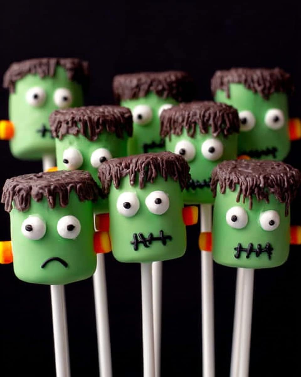 The image shows seven green marshmallow pops shaped like Frankenstein heads on white sticks. Each pop has a smooth green layer for the face with a textured, uneven brown layer on top representing hair. The eyes are made of two white circles with black pupils, placed near the top center of each pop. Each face has a small black zigzag line for the mouth and a few red stitch marks on the forehead. Small orange sticks are attached on both sides of each marshmallow to imitate bolts. The background is a plain black color. photo taken with an iphone --ar 4:5 --v 7