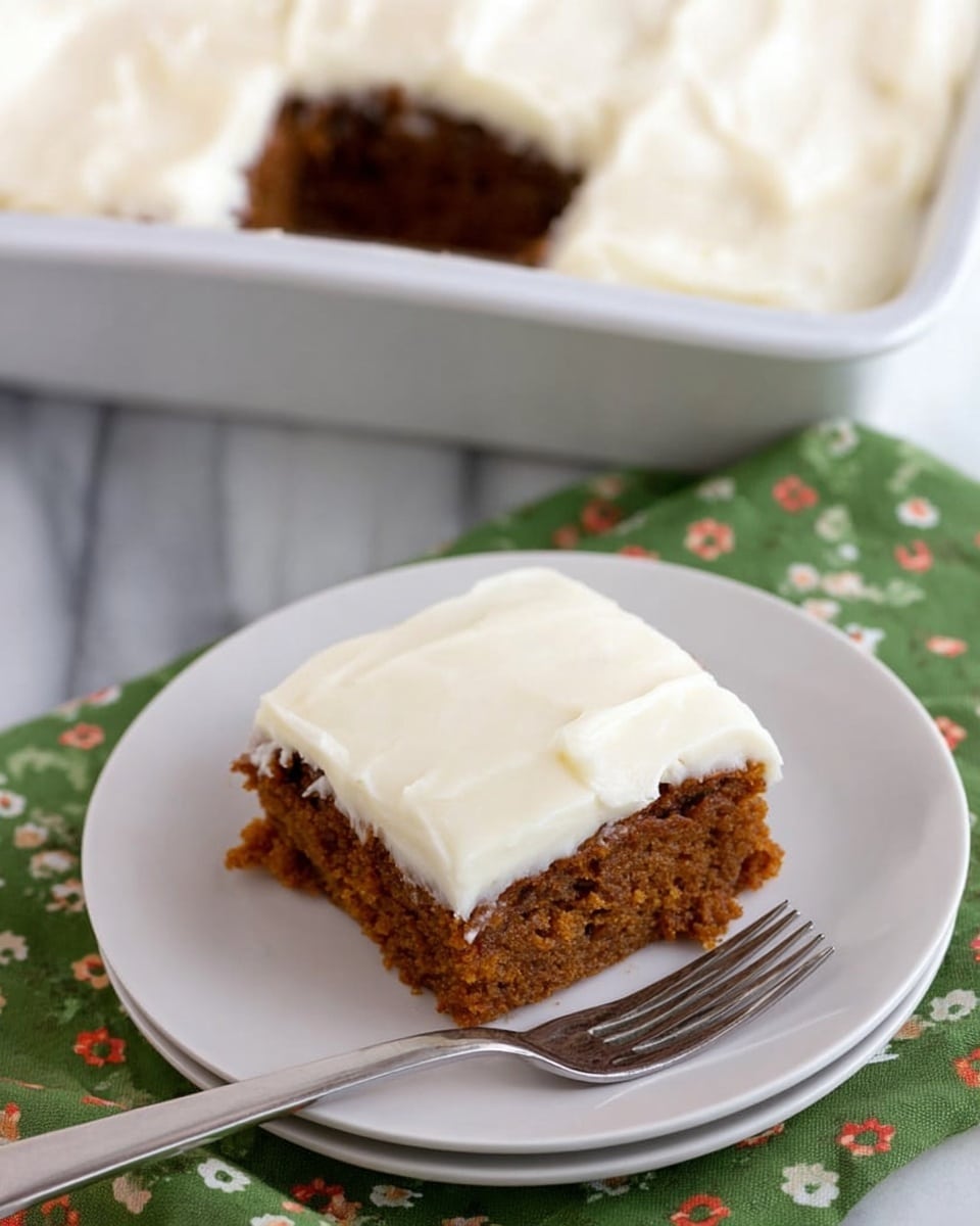 A square piece of carrot cake sits on a white plate with a green napkin underneath, showing two layers: a thick, moist orange-brown cake base with visible small bits, topped by a thick, smooth, and creamy white frosting layer evenly spread on top. The plate is placed on a wooden surface with a light tone. In the background, there is a white frosting-covered square cake with a missing piece in a dark baking pan on a metal cooling rack. A fork is resting on the edge of the plate near the cake slice. photo taken with an iphone --ar 4:5 --v 7