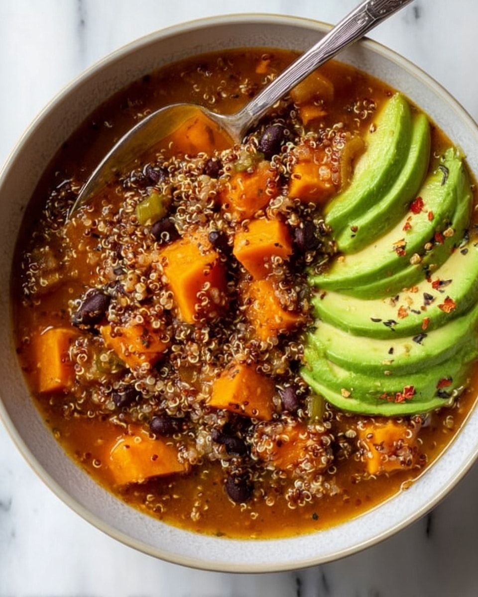 A close-up of a white bowl filled with a stew that has three main layers: at the bottom, small quinoa grains with a light, soft texture mixed with dark black beans spread evenly; in the middle, large soft orange sweet potato cubes scattered throughout the quinoa and beans; on the right side of the bowl, thin slices of green avocado neatly placed in a row with cracked black pepper sprinkled on top. A silver spoon dips into the stew on the left side inside the bowl. The bowl is set on a white marbled surface. Photo taken with an iphone --ar 4:5 --v 7