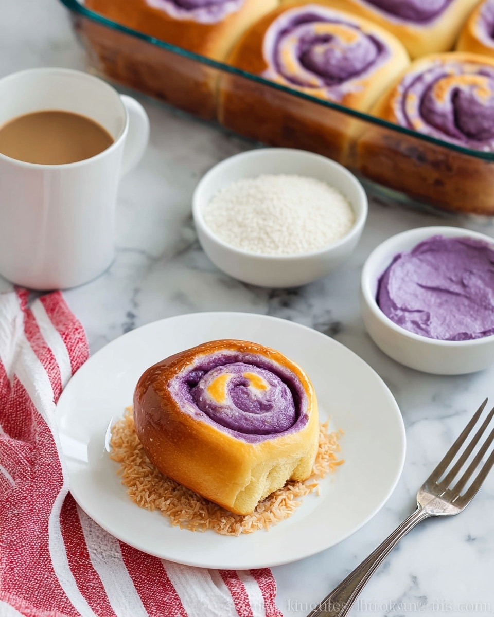 The image shows a close-up of a single bread roll with a purple and golden brown swirl pattern on top, placed on shredded brown coconut on a white plate. Behind the plate, there is a glass baking dish with several similar bread rolls, all golden brown with a visible purple swirl inside. A small white bowl filled with white granulated sugar and another white bowl containing a scoop of bright purple mashed filling are nearby. A white cup of dark brown coffee sits on a white saucer, and a silver fork is placed next to the plate. The entire scene is set on a white marbled surface with a red and white striped cloth in the background. photo taken with an iphone --ar 4:5 --v 7
