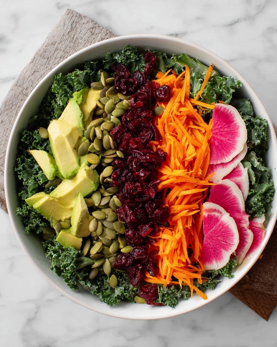 A white bowl filled with a fresh salad is shown on a white marbled surface. The bottom layer is dark green kale leaves, forming a full base. On top, there are four distinct rows: the first row has bright green avocado chunks, the second row features bright orange shredded carrots, the third row includes dark red shredded beets, and the fourth row is a mix of light green pumpkin seeds scattered over round slices of pink and white watermelon radish. Small dark red dried cranberries are scattered near the avocado. Photo taken with an iphone --ar 4:5 --v 7