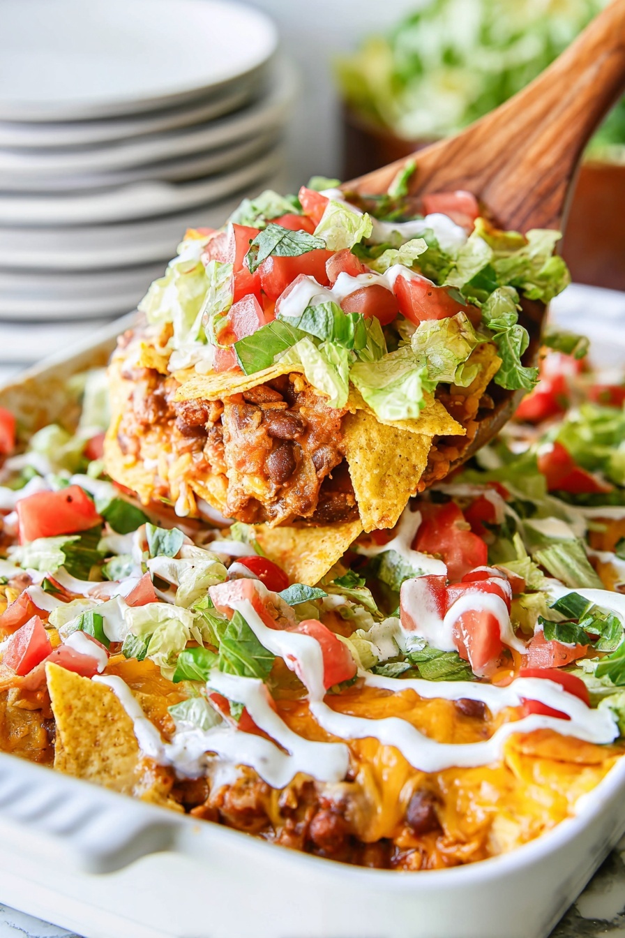 A white oval dish holds a layered taco casserole with five visible layers. The bottom layer is a mix of cooked chicken pieces and red sauce, covered by a golden-yellow crushed tortilla chip layer. On top of this is a bright green leafy lettuce layer mixed with small red tomato chunks. The dish is finished with white sour cream drizzled in thin diagonal lines across the surface. The dish rests on a white marbled surface. photo taken with an iphone --ar 2:3 --v 7 - Loaded Chicken Taco Casserole, chicken taco casserole, cheesy taco bake, Mexican-inspired chicken casserole, easy taco casserole recipe