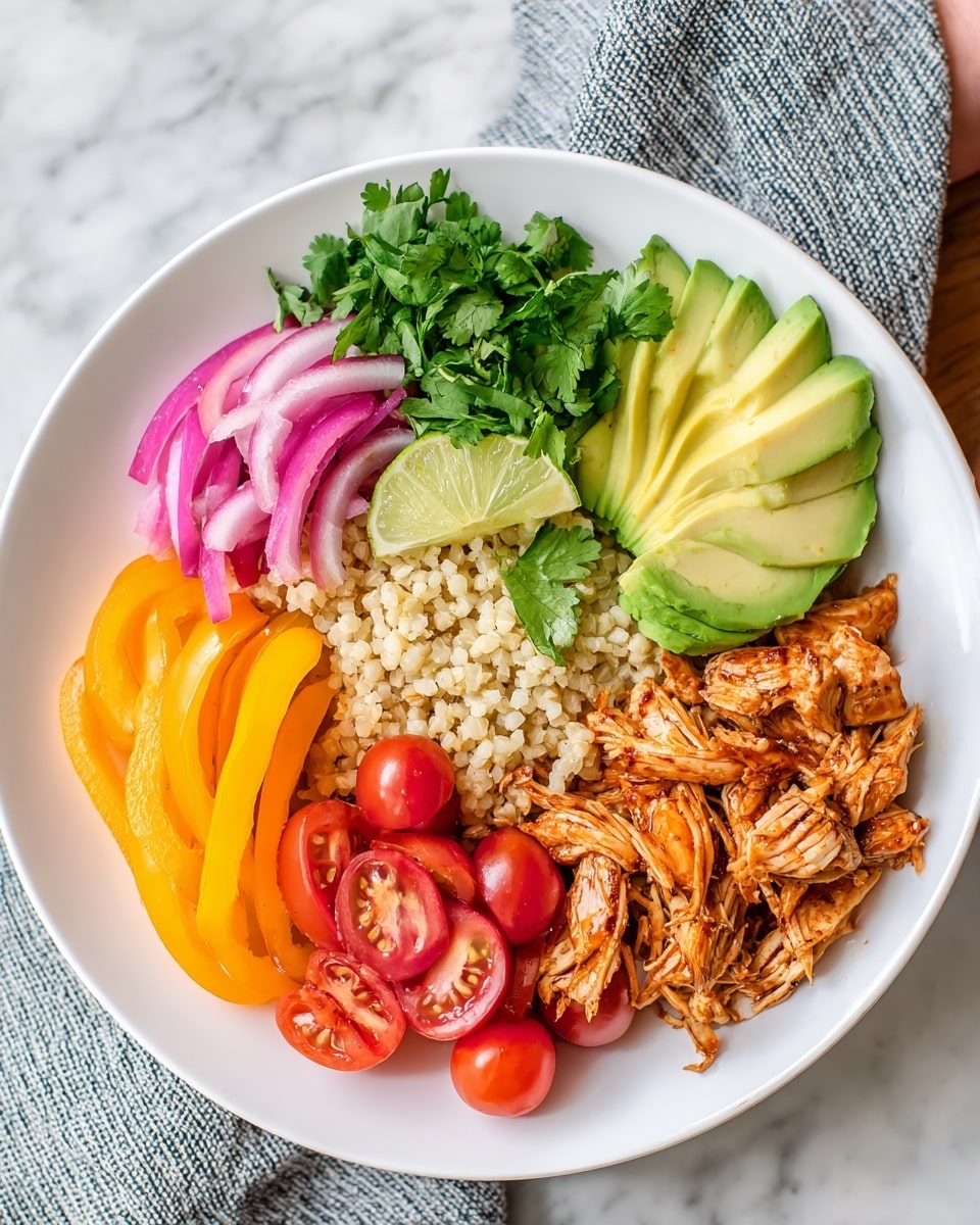 A white plate sits on a white marbled texture with a striped cloth underneath. On the plate, there is a base layer of beige cauliflower rice spread in the center. On the right side, there are several pieces of shredded orange-brown chicken. Above the chicken, there are thin slices of light green avocado stacked in a fan shape. To the left of the avocado, there are pale pink pickled onion rings. Under the onion rings, fresh green cilantro leaves sit next to a wedge of light green lime. Below the lime, there are bright yellow sliced bell peppers. At the bottom of the plate, there are halved bright red cherry tomatoes clustered together. Photo taken with an iphone --ar 4:5 --v 7
