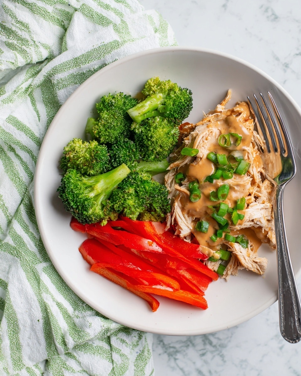 A white plate is placed on a white marbled surface with a green and white striped cloth underneath. On the plate, there are three main sections: to the left, bright green broccoli florets with a fresh texture; below that, slices of red bell pepper with a smooth and shiny skin; taking up the right half of the plate, shredded light beige chicken covered with a thick, brown sauce and garnished with small green onion pieces. A silver fork rests on the right edge of the plate. Photo taken with an iphone --ar 4:5 --v 7