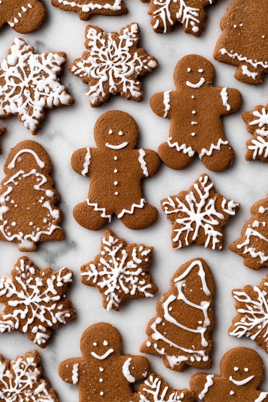 The image shows many brown gingerbread cookies shaped like gingerbread people, snowflakes, small gingerbread figures, and Christmas trees, all laid out flat on a white marbled surface. Each cookie is decorated with white icing in different patterns: the gingerbread people have wavy lines on their arms and legs and small dots on their bodies, the snowflakes show detailed white icing lines mimicking snowflake shapes, and the trees and smaller cookies have simple white icing designs. The cookies have a smooth texture and are close together without overlapping. photo taken with an iphone --ar 2:3 --v 7 - Soft Gingerbread Cookies, gingerbread cookies, soft cookie recipes, holiday cookies, spiced cookie recipe