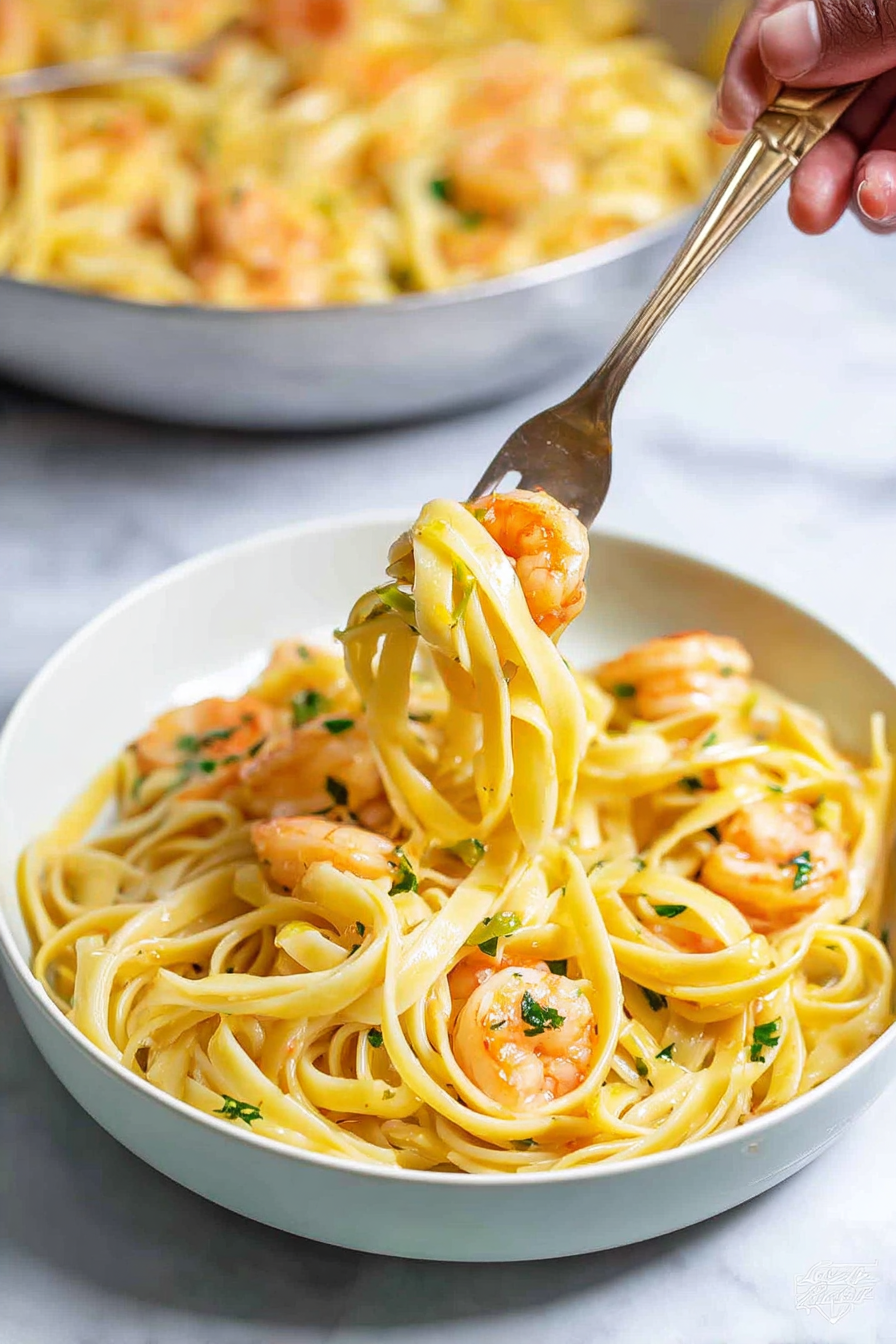 The image shows a white bowl filled with a shrimp pasta dish on a white marbled surface. The bottom layer has long, thick noodles in a light yellow color, tangled and covering the entire bowl. Scattered evenly on top are small cooked shrimp with a light orange color and slightly shiny texture. Finely chopped green herbs are sprinkled over the dish, adding a touch of color contrast. In the foreground, a woman's hand holds a silver fork lifting some noodles and two pieces of shrimp from the bowl. Behind this, a larger white bowl filled with the same shrimp pasta rests blurred in the background. The lighting highlights the glossy texture of the noodles and shrimp, making the dish look fresh and appetizing. photo taken with an iphone --ar 2:3 --v 7 - Creamy Garlic Shrimp Pasta, Shrimp Pasta Recipe, Garlic Shrimp Pasta, Easy Creamy Shrimp Pasta, Quick Seafood Pasta