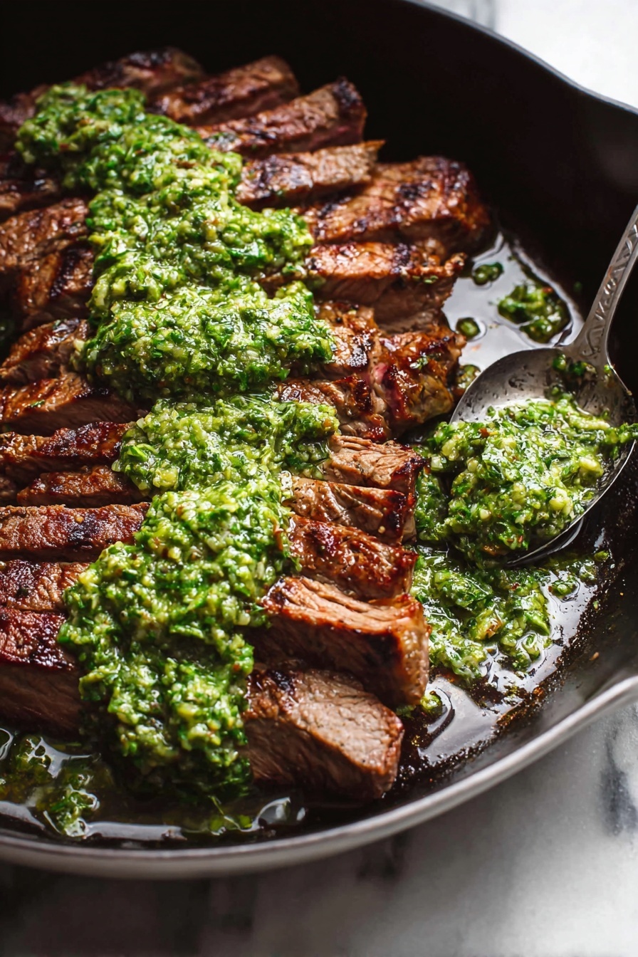 A dark pan holds a piece of grilled meat sliced into thick, even strips arranged compactly in a slightly curved line. The meat has a rich, brown color with visible grill marks, and a rough texture indicating it is well-cooked. On top of the meat, a thick, chunky green sauce is spread generously, with bits of herbs and oil visible. A spoon with more green sauce sits in the corner of the pan, with some sauce spilled around it. The pan rests on a white marbled surface. photo taken with an iphone --ar 2:3 --v 7 - Flank Steak with Chimichurri Sauce, flank steak, chimichurri recipe, grilled steak with chimichurri, easy steak dishes
