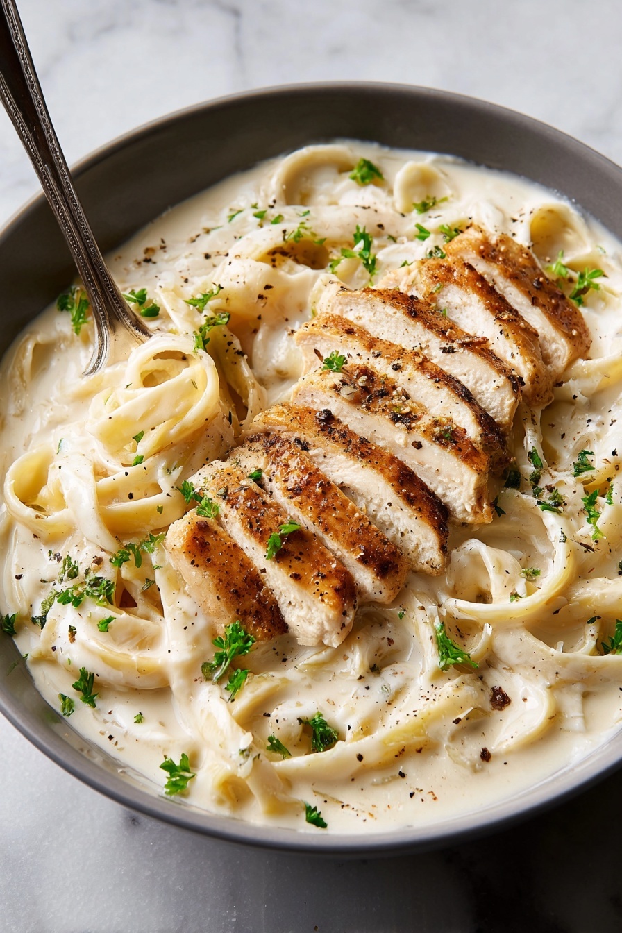The dish shows a white plate filled with thick, creamy white fettuccine pasta covered in a smooth white sauce. On top of the pasta, there are five slices of grilled chicken with a light brown sear, arranged in a line slightly slanting from the bottom right to the center. The sauce swirls around the pasta and chicken, with some black pepper sprinkled evenly over the whole dish. Small green parsley leaves are scattered on top, adding color contrast. A metal fork is resting on the left side, slightly lifting some pasta strands. The background is a white marbled texture. Photo taken with an iphone --ar 2:3 --v 7 - Creamy Chicken Alfredo Pasta, easy homemade Alfredo sauce, chicken pasta recipes, quick weeknight dinner ideas, restaurant-style chicken Alfredo