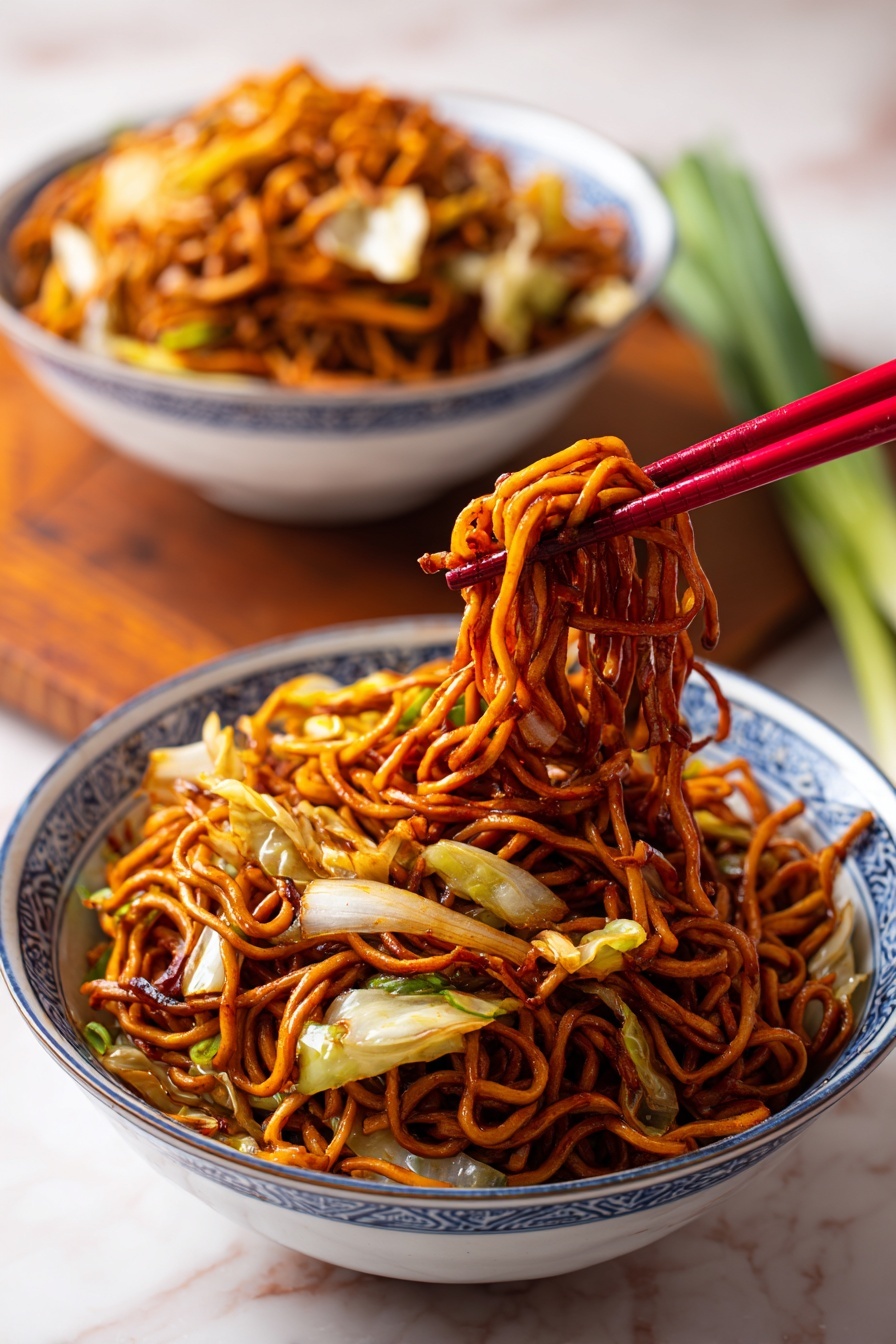 A bowl of stir-fried noodles with a glossy reddish-brown sauce, mixed with thin slices of white cabbage and other vegetables, held by red chopsticks above the bowl. The noodles are thick and tangled, with a shiny, slightly oily texture. In the background, a similar bowl filled with the same noodle dish sits on a white marbled surface with a wooden board and green onion behind it. The bowls are white with blue patterns on the outside. Photo taken with an iphone --ar 2:3 --v 7 - Easy Restaurant-Style Chicken Lo Mein, Chicken Lo Mein, Chinese Chicken Noodles, Homemade Lo Mein, Quick Chicken Stir Fry