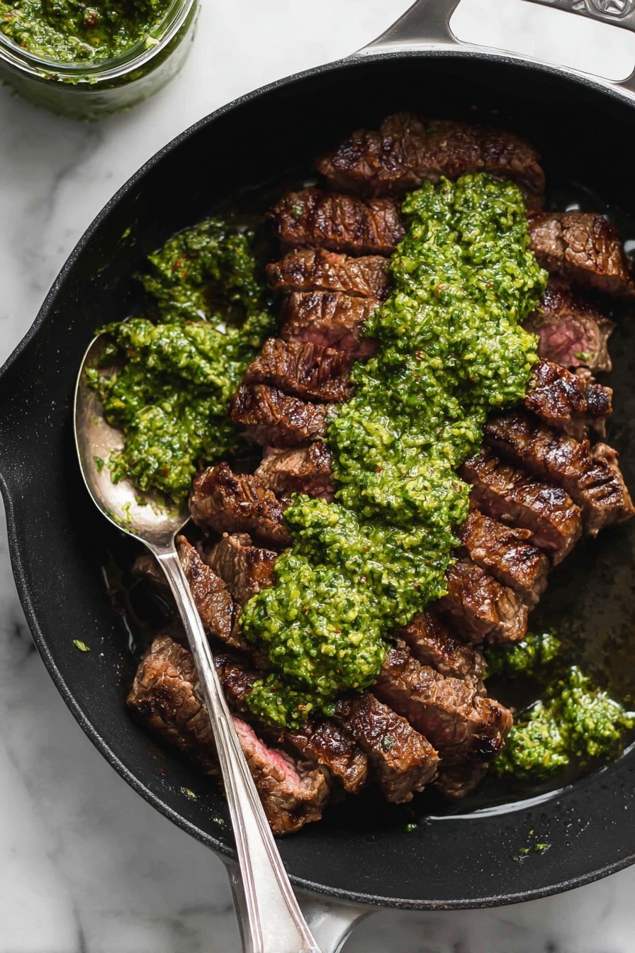 A black pan holds several slices of cooked steak arranged side by side, showing a rich brown grilled texture on top. A bright green sauce with a chunky, fresh texture is spread thickly over the middle of the steak, with some spilling onto the pan. A silver spoon rests in the pan near the upper left side, coated with some of the green sauce. The pan is set on a white marbled surface, and a jar of extra green sauce is partly visible in the top left corner of the image. photo taken with an iphone --ar 2:3 --v 7 - Flank Steak with Chimichurri Sauce, flank steak, chimichurri recipe, grilled steak with chimichurri, easy steak dishes