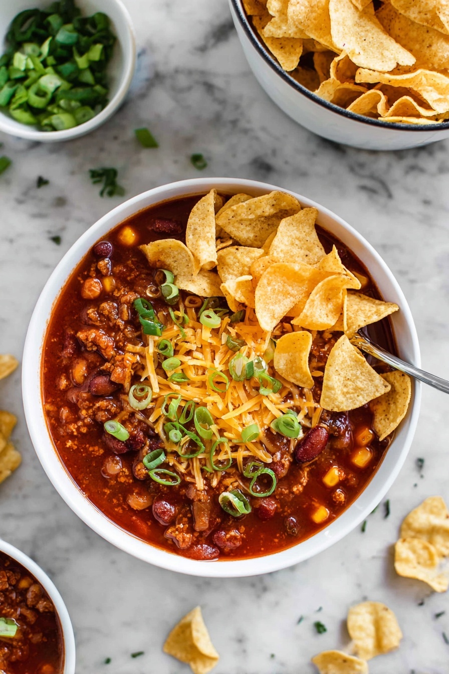 A white bowl holds a thick chili soup with a rich deep red color filled with chunky dark red beans, pieces of meat, and bits of yellow cheese melted on top and mixed in. On the surface of the chili, there is a layer of golden crunchy tortilla chips scattered in the middle, topped with chopped fresh green onions providing bright contrast. The bowl sits on a white marbled surface, with another bowl of tortilla chips blurred in the background. Some green herbs and a few chopped green onions are scattered around the bowl outside. Photo taken with an iphone --ar 2:3 --v 7 - Quick and Easy Taco Soup, taco soup recipe, quick dinner ideas, one-pot taco soup, flavorful weeknight meals