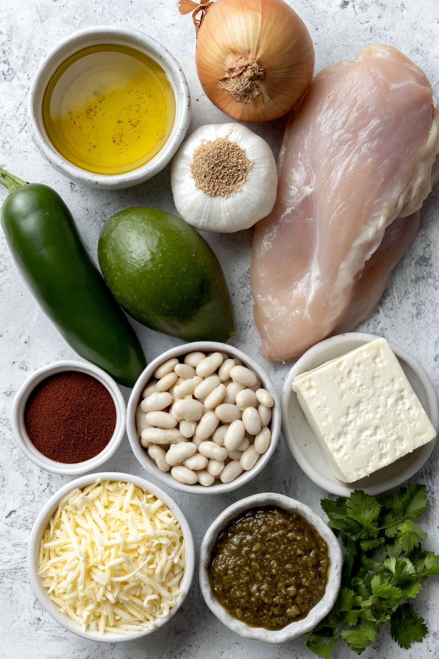 Flat lay of a small white ceramic bowl of extra virgin olive oil, one whole medium yellow onion, four peeled garlic cloves, two fresh poblano peppers, one green jalapeño pepper, a small white ceramic bowl of ground cumin, a small white ceramic bowl of smoked paprika, a small white ceramic bowl of chili powder, a raw boneless, skinless chicken breast, a small white ceramic bowl of low-sodium chicken broth, a block of cream cheese, a small white ceramic bowl of drained white beans, a small white ceramic bowl of salsa verde, a small white ceramic bowl of shredded cheddar cheese, a small white ceramic bowl of fresh chopped cilantro, one whole avocado, one whole lime with zest, placed on a clean white marble surface, soft natural light, photo taken with an iPhone, professional food photography style, fresh ingredients, white ceramic bowls, no bottles, no duplicates, no utensils, no packaging --ar 2:3 --v 7 --p m7354615311229779997 - Creamy Chicken Chili, Creamy Chicken Chili recipe, Best chicken chili, Comforting chili recipes, Easy creamy chili