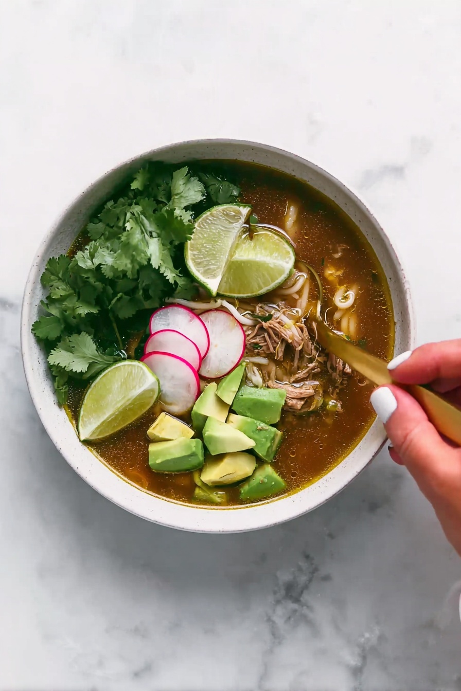 A white bowl filled with soup that has a brownish broth at the bottom layer mixed with pieces of shredded meat and small white noodles. On top of the soup, there are bright green chunks of avocado stacked on one side and thin slices of radish with a pale pink color beside them. Fresh green cilantro leaves are also scattered over the soup. A gold spoon is placed inside the bowl, partially submerged in the broth. Above the bowl, a woman's hand holding a lime wedge is about to squeeze it into the soup. The surface beneath the bowl is a white marbled texture. photo taken with an iphone --ar 2:3 --v 7 - Slow Cooker Chicken Posole Verde, easy Mexican Posole Verde, healthy slow cooker dinner, comforting chicken stew, Mexican green chili soup